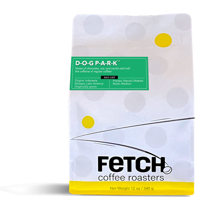 D-O-G P-A-R-K Half-caff has a green label offset to the left and toward the top of the white reclosable coffee bag. The bottom of the bag has a yellow band, and the logo shows a bean sitting at the base of the 'h' in Fetch.