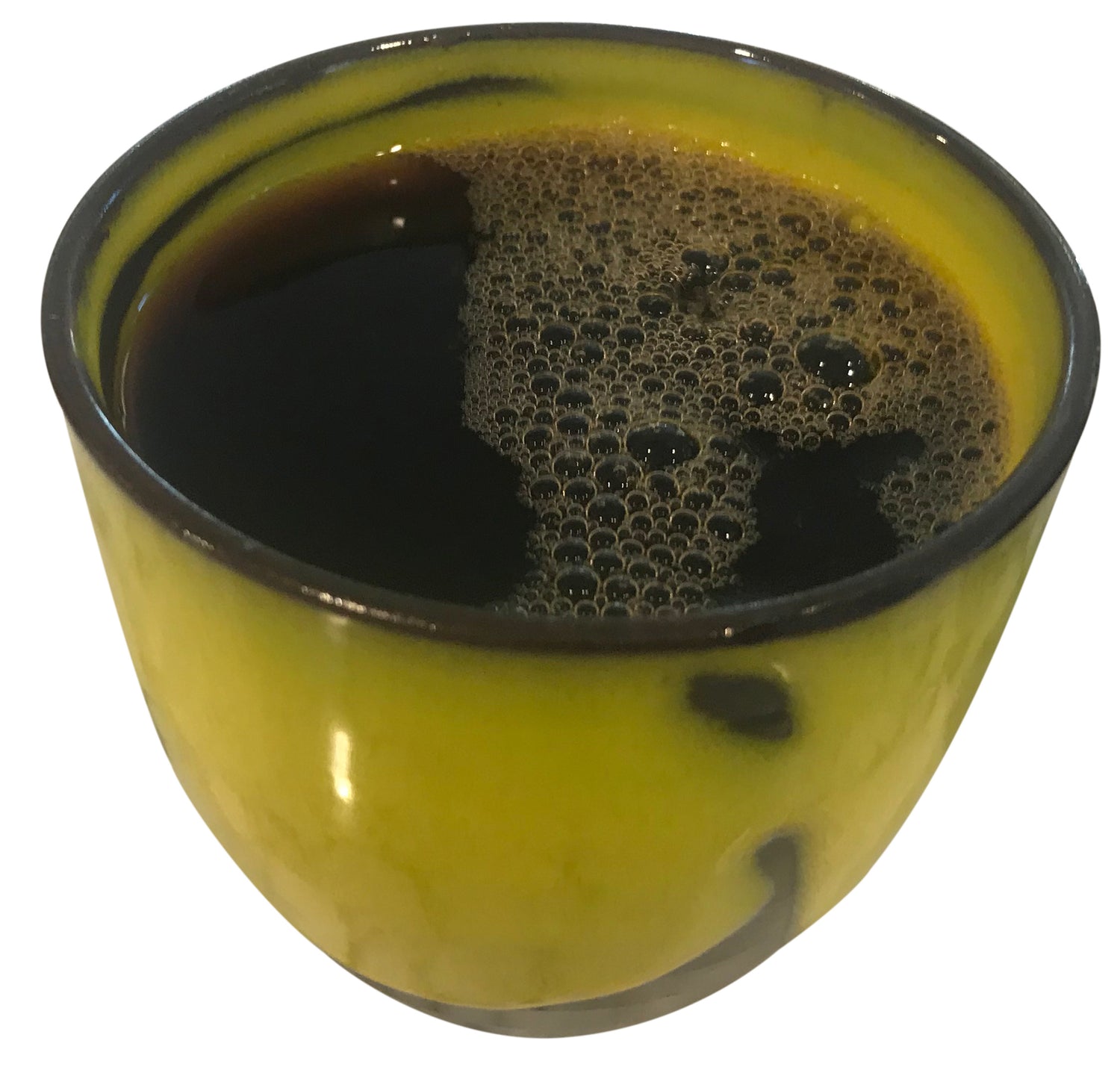 a cup of freshly poured black coffee in a yellow handmade cup