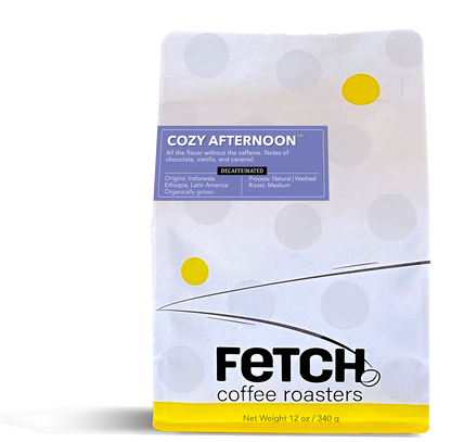 Cozy Afternoon decaf has a purple label offset to the left and toward the top of the white recloseable top of the coffee bag.  The bottom of the bag has a yellow band, and the logo shows a bean sitting at the base of the 'h' in Fetch.
