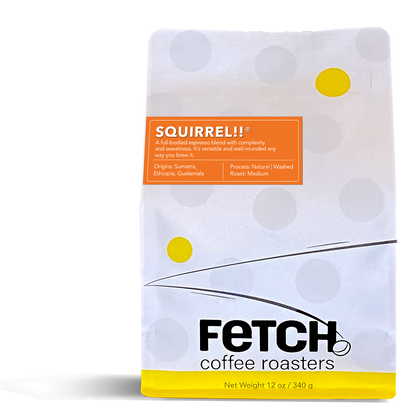 Squirrel!! has an orange label offset to the left and toward the top of the white recloseable top of the coffee bag. The bottom of the bag has a yellow band, and the logo shows a bean sitting at the base of the 'h' in Fetch.